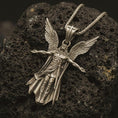 Load image into Gallery viewer, Bronze Archangel Michael pendant necklace with an oxidized finish resting on textured volcanic rock, captured in a close-up premium studio composition.