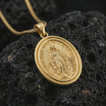 Load image into Gallery viewer, Gold plated Miraculous Medal pendant necklace presented on porous volcanic rock, highlighting the round devotional medallion design in a luxurious close-up jewelry image.