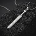 Load image into Gallery viewer, Polished silver Dragonslayer sword pendant necklace displayed on black volcanic rock, shown in a refined macro product shot with long blade detail and rugged forged texture.