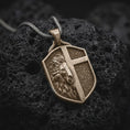 Load image into Gallery viewer, Bronze lion cross shield pendant on black volcanic stone with oxidized depth and strong relief details.