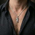 Load image into Gallery viewer, Polished silver seahorse necklace worn on the neck in a close lifestyle frame, highlighting the sculpted marine texture and elegant curled silhouette