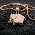 Load image into Gallery viewer, Rose gold plated geometric elephant pendant with origami-style folds, sleek modern silhouette, and elegant minimalist design resting on volcanic rock in an elegant close-up product presentation