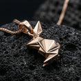 Load image into Gallery viewer, Rose gold plated geometric rabbit pendant with origami-style folds, sleek modern bunny silhouette, and elegant minimalist design resting on volcanic rock in an elegant close-up product presentation