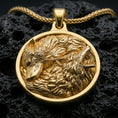 Load image into Gallery viewer, Gold plated twin wolf pendant with howling wolf relief, resting wolf profile, and richly layered fur detailing showcased on black volcanic rock in a refined macro jewelry image