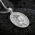 Load image into Gallery viewer, A 925 sterling silver oval cat medallion on black volcanic rock, polished silver shine emphasizing crisp sculpted details.