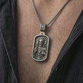 Load image into Gallery viewer, Oxidized Sacred Heart pendant necklace worn on the neck, styled in a dark lifestyle portrait with an open shirt and masculine presentation.