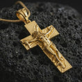 Load image into Gallery viewer, Gold plated symbolic cross pendant presented on porous volcanic rock, highlighting the dramatic sacred silhouette in a luxurious close-up jewelry image.