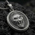 Load image into Gallery viewer, Oxidized roaring gorilla pendant with fierce open-mouth ape relief, oval medallion frame, and bold primal animal silhouette displayed on dark volcanic rock in a close-up luxury jewelry composition