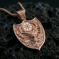 Load image into Gallery viewer, Rose gold plated Norse stag necklace with Celtic knotwork, antler motif, and shield-shaped woodland design resting on volcanic rock in an elegant close-up product presentation