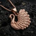 Load image into Gallery viewer, Rose gold plated swan necklace with detailed wing relief, decorative feather texture, and graceful bird form resting on volcanic rock in an elegant close-up product presentation