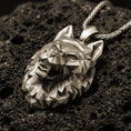 Load image into Gallery viewer, Bronze polygonal wolf pendant with faceted geometric wolf head, angular sculpted planes, and bold spirit animal silhouette displayed on dark volcanic rock in a close-up luxury jewelry composition