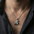 Load image into Gallery viewer, Polished silver origami swan necklace with folded angular form and abstract bird design worn on the neck in a close lifestyle frame, highlighting the clean geometric structure and refined craftsmanship