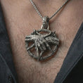 Load image into Gallery viewer, Oxidized bad dream catcher pendant necklace worn on the neck, styled in a dark lifestyle portrait with an open shirt and masculine presentation.