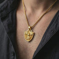 Load image into Gallery viewer, Gold plated Fortiores Una eagle shield pendant necklace worn on the neck, captured on a human model in a premium dark-toned lifestyle frame.