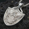 Load image into Gallery viewer, Polished silver Fortiores Una eagle shield pendant necklace displayed on black volcanic rock, shown in a refined macro product shot with detailed patriotic crest, eagle wings, and banner relief.