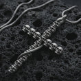Load image into Gallery viewer, Sterling silver skull cross pendant necklace with an oxidized finish resting on textured volcanic rock, captured in a close-up premium studio composition.