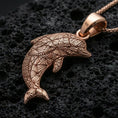 Load image into Gallery viewer, Rose gold plated dolphin pendant necklace on dark volcanic rock, photographed in a detailed premium studio macro view.
