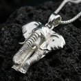 Load image into Gallery viewer, Polished silver elephant pendant necklace displayed on black volcanic rock, shown in a refined macro product shot with sculpted trunk and tusk details.
