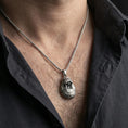 Load image into Gallery viewer, Oxidized walrus pendant necklace worn on the neck, styled in a dark lifestyle portrait with an open shirt and masculine presentation.