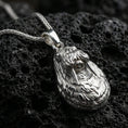 Load image into Gallery viewer, Polished silver walrus pendant necklace displayed on black volcanic rock, shown in a refined macro product shot with detailed tusk and fur texture.