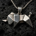 Load image into Gallery viewer, Sterling silver origami elephant pendant necklace with an oxidized finish resting on textured volcanic rock, captured in a close-up premium studio composition.