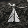 Load image into Gallery viewer, Polished silver origami airplane pendant necklace displayed on black volcanic rock, shown in a refined macro product shot with clean geometric folds and sharp aviation-inspired lines.