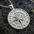 Load image into Gallery viewer, Polished silver compass pendant necklace displayed on black volcanic rock, shown in a refined macro product shot with detailed cardinal directions and raised star relief.