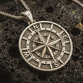 Load image into Gallery viewer, Bronze compass pendant necklace with an oxidized finish resting on textured volcanic rock, captured in a close-up premium studio composition.