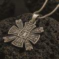 Load image into Gallery viewer, Bronze Norse Celtic cross pendant with an oxidized finish resting on textured volcanic rock, captured in a close-up premium studio composition.