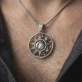 Load image into Gallery viewer, Oxidized sun and moon pendant necklace worn on the neck, styled in a dark lifestyle portrait with an open shirt and masculine presentation.