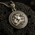 Load image into Gallery viewer, Bronze horse head pendant necklace with an oxidized finish resting on textured volcanic rock, captured in a close-up premium studio composition.