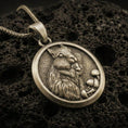 Load image into Gallery viewer, Bronze squirrel pendant necklace with an oxidized finish resting on textured volcanic rock, captured in a close-up premium studio composition.