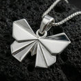 Load image into Gallery viewer, Polished silver origami butterfly pendant necklace displayed on black volcanic rock, shown in a refined macro product shot with sharp folded wing details.