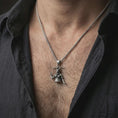 Load image into Gallery viewer, Oxidized Baphomet pendant necklace worn on the neck, styled in a dark lifestyle portrait with an open shirt and masculine presentation.