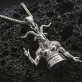 Load image into Gallery viewer, Polished silver Baphomet pendant necklace displayed on black volcanic rock, shown in a refined macro product shot with horned occult figure, pentagram detail, and sculptural relief.