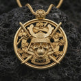 Load image into Gallery viewer, Gold plated samurai skull pendant necklace presented on porous volcanic rock, highlighting the gothic warrior motif in a luxurious close-up jewelry image.