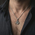 Load image into Gallery viewer, Oxidized Master Mason pendant necklace worn on the neck, styled in a dark lifestyle portrait with an open shirt and masculine presentation.