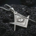 Load image into Gallery viewer, Polished silver Master Mason pendant necklace displayed on black volcanic rock, shown in a refined macro product shot with square and compass design and Eye of Providence detail.