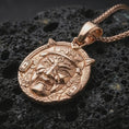 Load image into Gallery viewer, A rose gold plated Oni pendant on volcanic rock with warm tone emphasizing the mask contours and textured background.