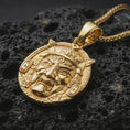 Load image into Gallery viewer, A gold plated Oni mask pendant on black volcanic stone with bright highlights across the facial features and ornamental frame.
