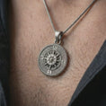 Load image into Gallery viewer, Oxidized steampunk compass pendant necklace worn on the neck, styled in a dark lifestyle portrait with an open shirt and masculine presentation.