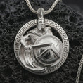 Load image into Gallery viewer, Polished silver Spartan warrior pendant necklace displayed on black volcanic rock, shown in a refined macro product shot with helmeted soldier, sword, shield, and Greek key border detail.