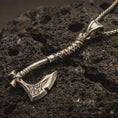Load image into Gallery viewer, Bronze battle axe pendant necklace with an oxidized finish resting on textured volcanic rock, captured in a close-up premium studio composition.