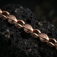 Load image into Gallery viewer, Rose gold plated evil eye link chain necklace on dark volcanic rock, photographed in a detailed premium studio macro view.