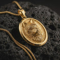 Load image into Gallery viewer, Gold plated snarling wolf pendant necklace presented on porous volcanic rock, highlighting the wild predator motif in a luxurious close-up jewelry image.
