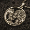 Load image into Gallery viewer, Bronze lion and bear family pendant necklace with an oxidized finish resting on textured volcanic rock, captured in a close-up premium studio composition.