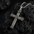 Load image into Gallery viewer, Sterling silver Orthodox cross pendant necklace backside with an oxidized finish resting on textured volcanic rock, captured in a close-up premium studio composition.
