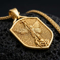 Load image into Gallery viewer, Gold plated Saint Michael shield pendant necklace presented on porous volcanic rock, highlighting the heraldic shape and sacred defender design in a luxurious close-up jewelry image.