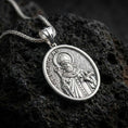 Load image into Gallery viewer, Polished silver Saint Nicholas pendant necklace displayed on black volcanic rock, shown in a refined macro product shot with detailed bishop figure, staff, and engraved lettering.