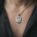 Load image into Gallery viewer, Polished silver cobra shield pendant necklace worn on the neck, shown against the chest in a clean and striking everyday wear composition.